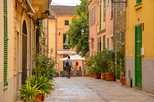 Woman walking down narrow street in the old town of Alcudia, Alcudia, Majorca, Balearic Islands