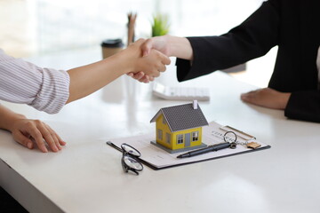 Businesswoman or real estate agent shakes hands with a client and asks them to legally sign a contract of agreement.