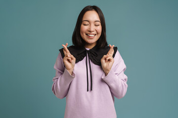 Young asian woman laughing while fingers crossed for good luck