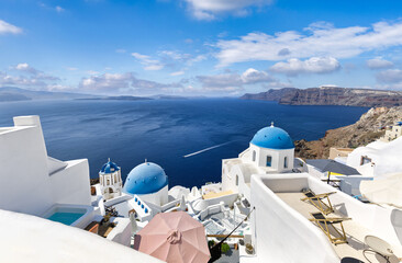 View of Oia town in Santorini island in Greece. Famous Greek landscape, blue domes over white architecture. Luxury summer holiday destination, romantic travel scenic. Beautiful cityscape and blue sea