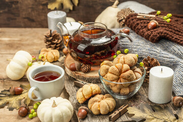 Fototapeta na wymiar Autumn tea concept. Cookies with pumpkin puree, black tea in a glass teapot, fall decor