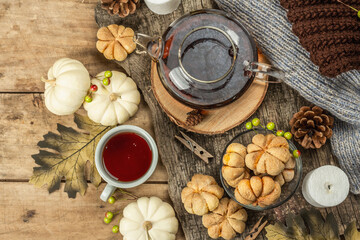 Autumn tea concept. Cookies with pumpkin puree, black tea in a glass teapot, fall decor