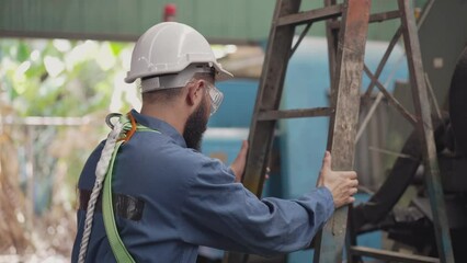 Male engineer or mechanic worker climbing on ladder to checking machine in the industrial factory. quality control, repair and maintenance before working.