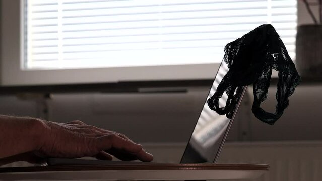 A man uses a computer keyboard to surf internet pornography