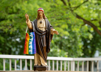 Jesus statue with the rainbow knit cap and LGBT pride flag with a peace sign 