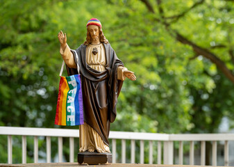Obraz premium Jesus statue with the rainbow knit cap and LGBT pride flag with a peace sign 