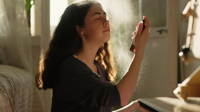 Portrait of young woman sprays a refreshing and moisturizing spray on her face. Summer heat. Skin care.