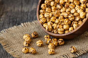 Roasted yellow chickpeas in bowl on wooden background, traditional turkish nut, leblebi
