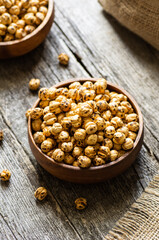 Roasted yellow chickpeas in bowl on wooden background, traditional turkish nut, leblebi