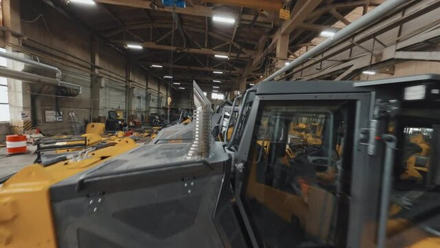 Drone tracking view of yellow dozers in progress at factory in afternoon
