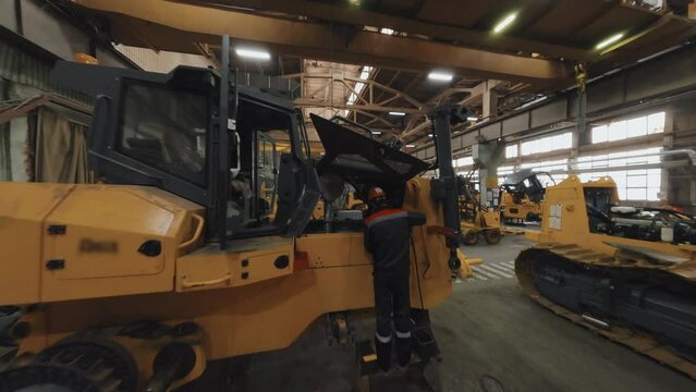 Drone footage of bulldozer factory with workmen inside