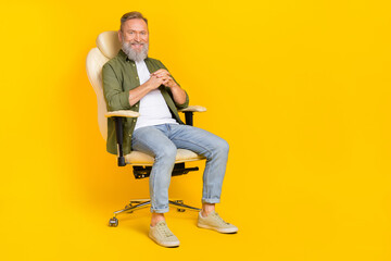 Full body portrait of cheerful aged person sitting chair have good mood isolated on yellow color background