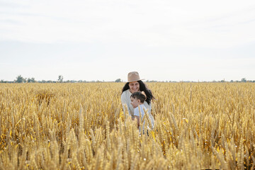 Happy family of mother and infant child walking on wheat field