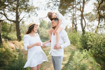 Fototapeta premium Happy pregnant couple with daughter in summer nature.