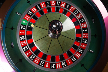Image with casino roulette wheel with ball on number 0.