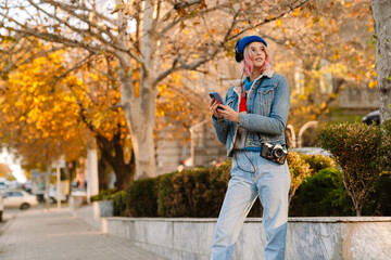 Young woman wearing hat using mobile phone while walking in park