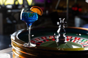 Blue alcoholic cocktail. Against the background of the roulette wheel.