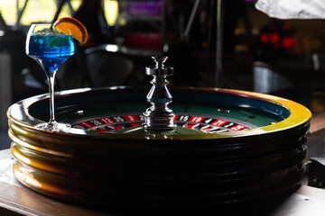 Blue alcoholic cocktail. Against the background of the roulette wheel.