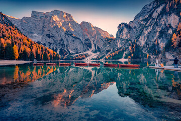 Photo shoot on the shore of Braies Lake with recreational boats. Calm autumn scene of Dolomite Alps, Italy, Europe. Traveling concept background..