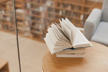 Open book on the table. Stack of books on coffee table at library. Back to school and education. Learning and reading. University library. Turning book pages.