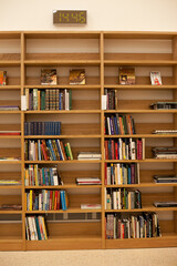 Wooden library shelves with books. Bookshelves with stacks of books. Bookstore or university or library.
