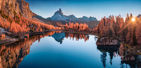 Panoramic autumn view from flying drone of popular tourist destination - Federa lake among red larch trees. Impressive sunrise in Dolomite Alps. Gorgeous morning scene of Italy, Europe. - obrazy, fototapety, plakaty
