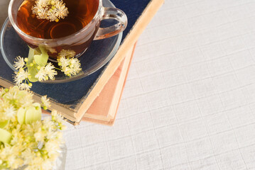 Linden herbal tea on a light pastel background. Old books. Copy space