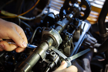 Fototapeta na wymiar Mercedes diesel engine repair. Hands with a mechanic repairing Mercedes parts. Valve clearance adjustment.