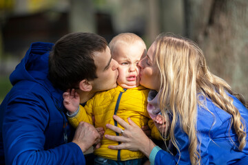 Happy family mom dad and little son. A woman and a man kiss a small child.