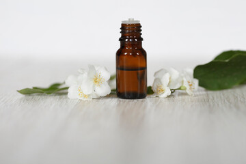 jasmine, Philadelphus essential oil (tincture, remedy, infusion) bottle with fresh jasmine  flowers on wooden table and white wall background. Flower essential oil. Herbal medicine.