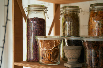 Jars with dried flowers and fruit on shelf in market