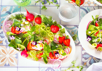 Spring summer salad with edible flowers pansy viola and fresh microgreens. greens and strawberries