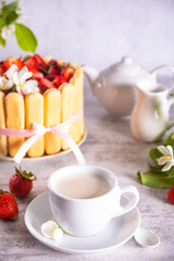 cup of milk teal, cake with fresh strawberries with flowers branch of apple tree