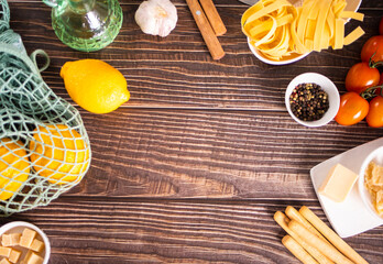 composition of healthy food ingredients for cooking italian pasta. Spaghetti, parmesan, basil, lemon on wooden kitchen rustic table. Top view. Copy space.