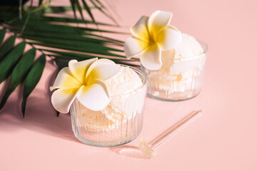 Delicious tropical flavors ice cream sorbet sundae decorated flower plumeria frangipani and palm leaf on the background . Summer food concept.