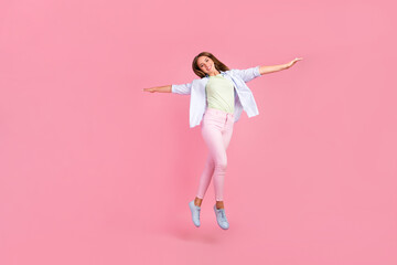 Full length portrait of overjoyed charming girl jump raise arms wings fly isolated on pink color background