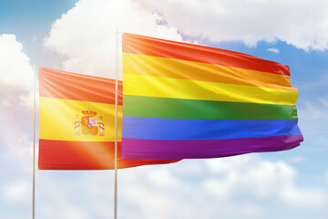 Sunny blue sky and flags of lgbt and spain