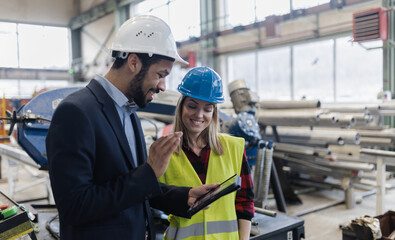 Engineering manager and mechanic worker doing routine check up in industrial factory and having video call.