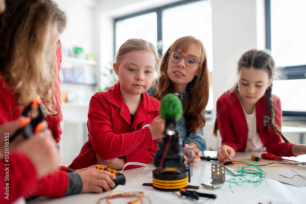 Wall mural group of kids with their teacher programming electric toys and robots at robotics classroom