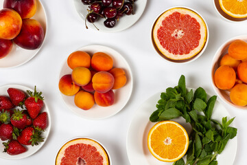 Fresh fruits on white plates, bright summer background