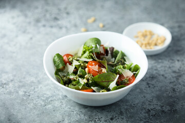 Healthy green salad with tomatoes, pesto and cheese