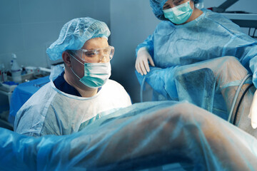 Male gynecologist and his assistant working with patient - obrazy, fototapety, plakaty