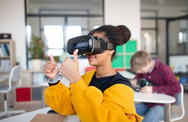 Happy student wearing virtual reality goggles at school in computer science class