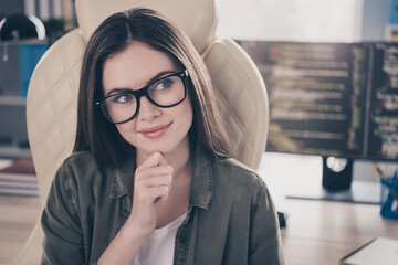 Portrait of attractive minded skilled girl sitting in chair deciding developing web startup task at workplace workstation indoors