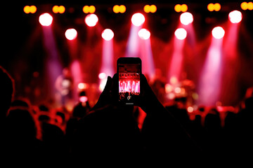 Holding a smartphone to record music concert. Mobile phone at a summer festival.