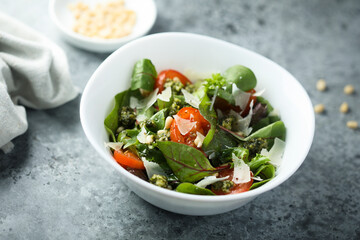 Healthy green salad with tomatoes, pesto and cheese