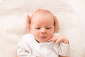 Unrecognizable mother holding her newborn son at home, close-up