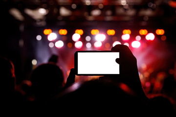 Smartphone in a hands on a music concert show, blank white screen mockup.