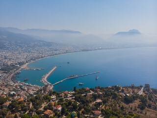 View from a height to the port of Alanya. Sea harbor. Mediterranean Sea. Lighthouses in the harbor at the exit from the water area of the port of Alanya. Turkey. Aerial photography.