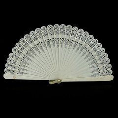 antique white fan on a black isolated background. fan with patterns close-up.